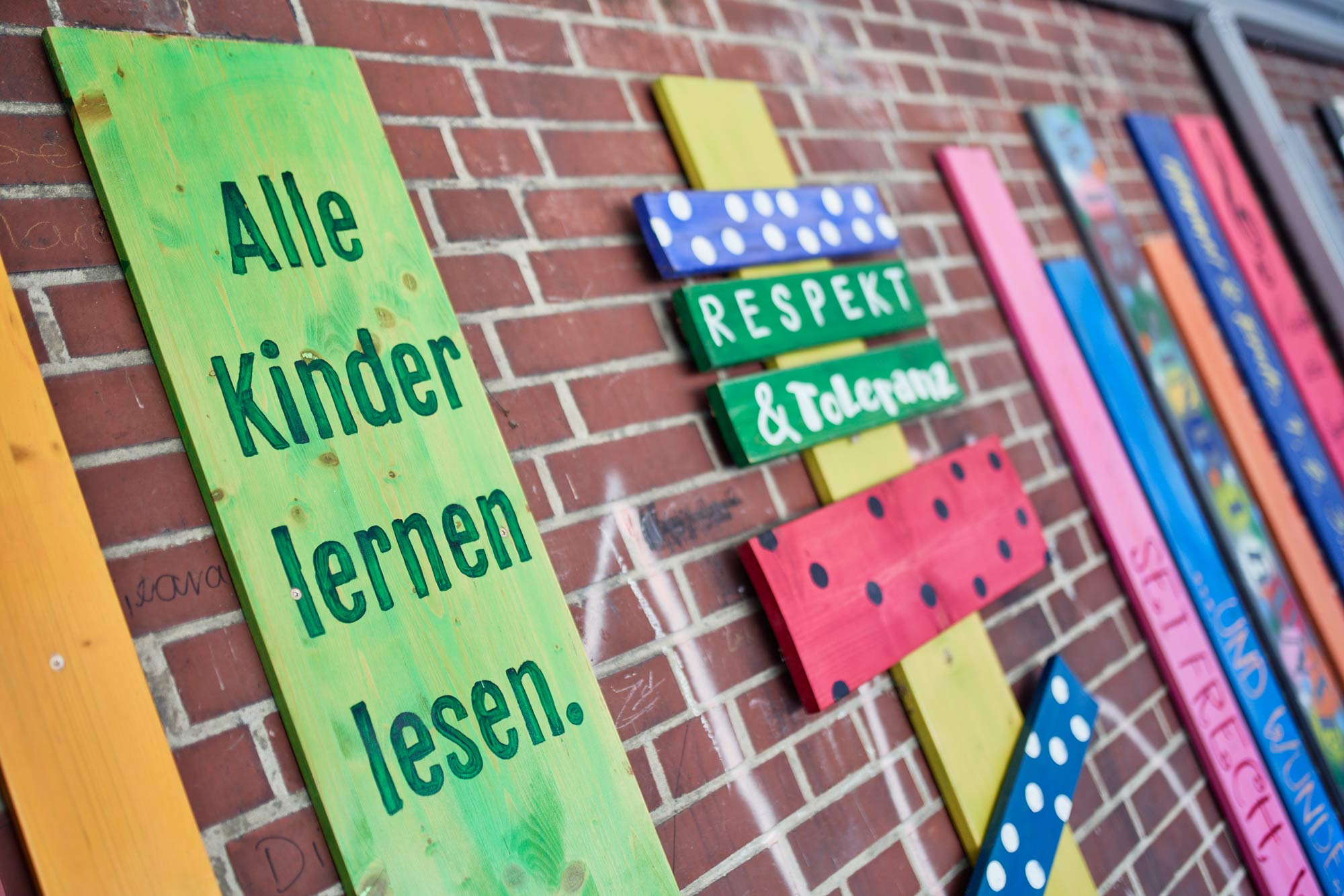 Selbstgebastelte Holzschilder mit den Aufschriften "Alle Kinder lernen lesen." und "Respekt & Toleranz"